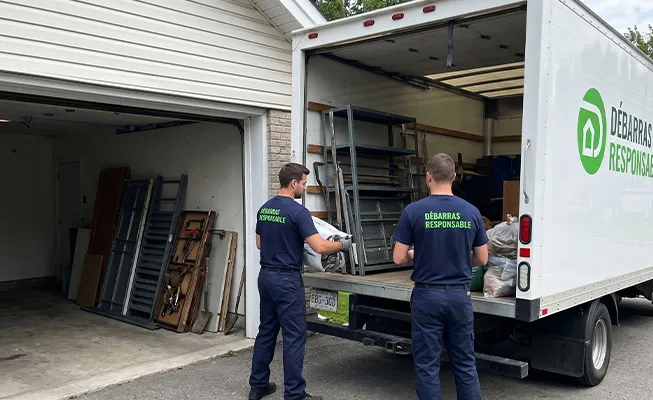Camion blanc Débarras Responsable (texte vert) garé devant un garage individuel, deux travailleurs chargeant des étagères métalliques et des sacs d'encombrants.