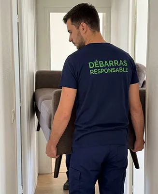 Professionnel de Débarras Responsable manœuvrant un canapé compact avec soin dans un couloir d'appartement étroit.